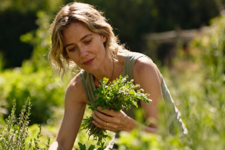 Femme européenne récoltant des herbes dans un jardin ensoleillé pour préparer des remèdes naturels